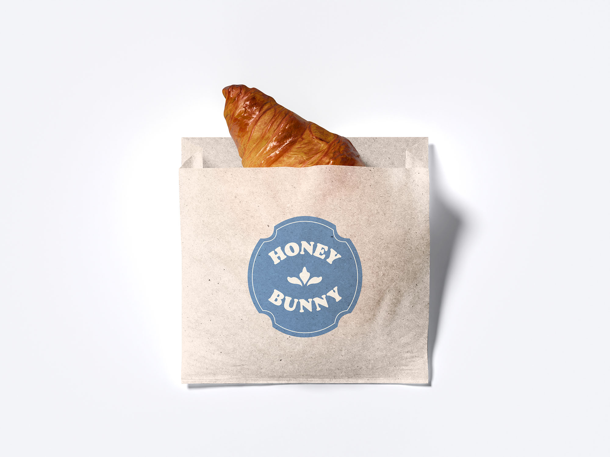Crossiant in a take out bag with the Honey Bunny Logo on it